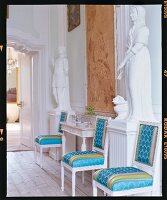 Gepolsterte Stühle in Weiß und Blau an Wand zwischen Statuen in Weiß