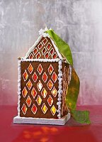 A lantern shaped like a gingerbread house, illuminated from within