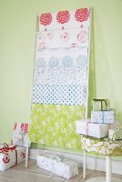 Wrapped gifts and floral patterned wrapping papers against pastel green wall