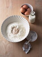 Flour and yeast in bowl beside milk and egg