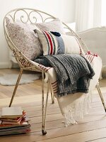 Kissen und Decken auf Vintage Metallstuhl in Weiß