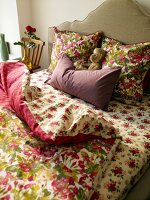 Red floral bed linen on bed against beige wall
