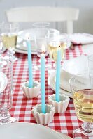 Gedeckter Tisch, 3 türkise Kerzen, rot-weiße Tischdecke, Teller, Gläser
