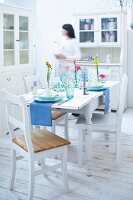 Table laid with plates, glasses and vase, woman in background, blurred