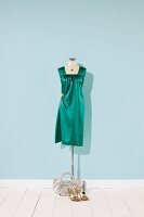 Green satin gown and necklace on mannequin
