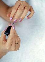 Close-up of woman's hands applying pink nail polish on nails