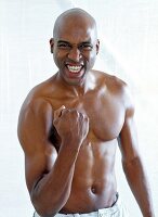 Portrait of happy shirtless bald man standing and making fist with excitement