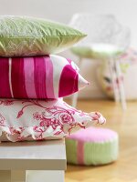 Pink, green and white cushions stacked on table