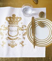 Golden-white plates on table mat with glass on side