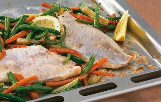 Close-up of redfish with blanched vegetables on baking sheet