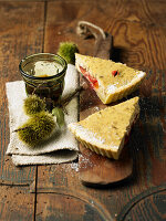 Two pieces of chestnuts, prunes and curd tart with glass of tea on wooden table