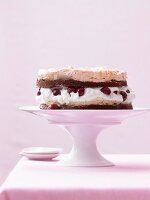 A meringue cake filled with marinated cherries and cream on a cake stand