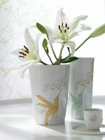 weiße Blumen in weißen Porzellanvasen mit Kolibris verziert