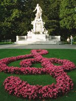 Pink begonia arranged in shape of Treble clef against Mozart monument