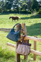 Two handbags hanging on wooden fence