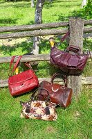 4 Handtaschen vor und am Zaun, rot, braun, Gänse gucken durch Zaun