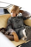 Woman wearing fur cap and coat sitting in car, looking away