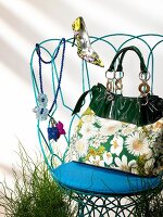 Handbag with daisy motif, floral patterned pumps, pearl necklace and pendant on chair