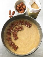 Pecans arranged with pie shell in baking tray, overhead view