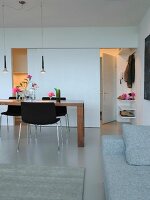 Dining table and chairs with view of kitchen behind sliding door and apartment entrance