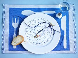 Plate with round menu card, fish, note and slice of bread