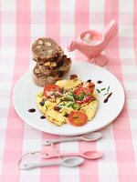 Cheesy scrambled eggs with tomatoes and balsamic vinegar served with a nut baguette