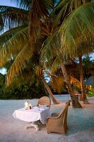 Tables laid on beach at dusk in Veligandu Island Resort, Maldives