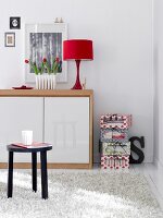 Red table lamp on wooden chest with shaggy rug on floor