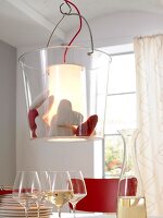 Suspension lamp filled with fabric hearts hanging above table with wine glasses