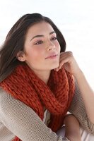 Dreamy woman wearing beige cardigan and red scarf, looking away and smiling