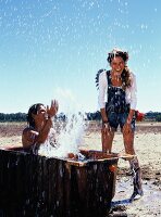 Man in bath tub splashing water on woman, laughing