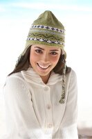 Portrait of beautiful woman wearing white cardigan and green knit cap, smiling widely