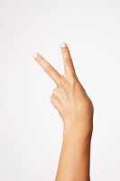 Close-up of hand indicating peace sign against white background