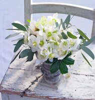 Ein Strauß weiße Christrosen steht uf einem Holzstuhl