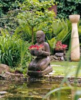 Balinese stone statue of woman kneeling in water pool