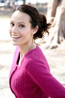 Portrait of beautiful brunette woman wearing pink cardigan smiling widely