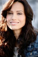 Portrait of beautiful woman with dark hair wearing denim jacket, smiling