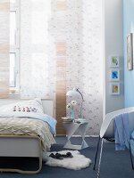 Bett vor Flächenvorhang im Schlafzimmer mit einer hellblauen Wand