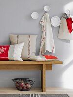 Sitzbank aus Holz mit Kissen in weiß rot, Geschirrtücher an der Wand