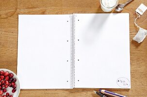 Notepad with blank pages, bowl of cranberries, yogurt and tea bags
