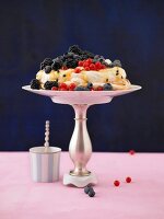 Pavlova with fresh berries and passion fruit sauce on a cake stand
