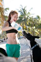 rothaarige Frau, gibt Hund Wasser Sommerspossen, sportlich