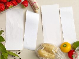 Vier leere Zettel eingerahmt von Gemüse, Obst & Gewürzen