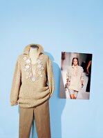 Langarm pullover with pearl buttons on clothes stand, photo of model on blue background