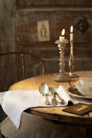 Table decorated with white cloth, cutlery, plates and candles
