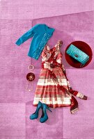 Chiffon dress decorated with stripes with red cardigan, purse and heels on pink background