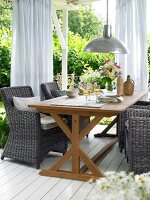 Wooden dining table with wicker chairs on terrace