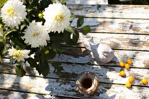 White chrysanthemums and bird figurine on wooden surface, overhead view