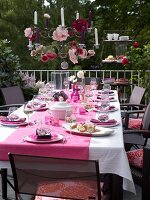 Table setting in pink with crockery and chandelier on terrace