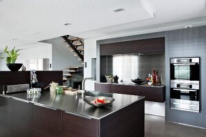 Modern kitchen in wood and stainless steel with stairs in background